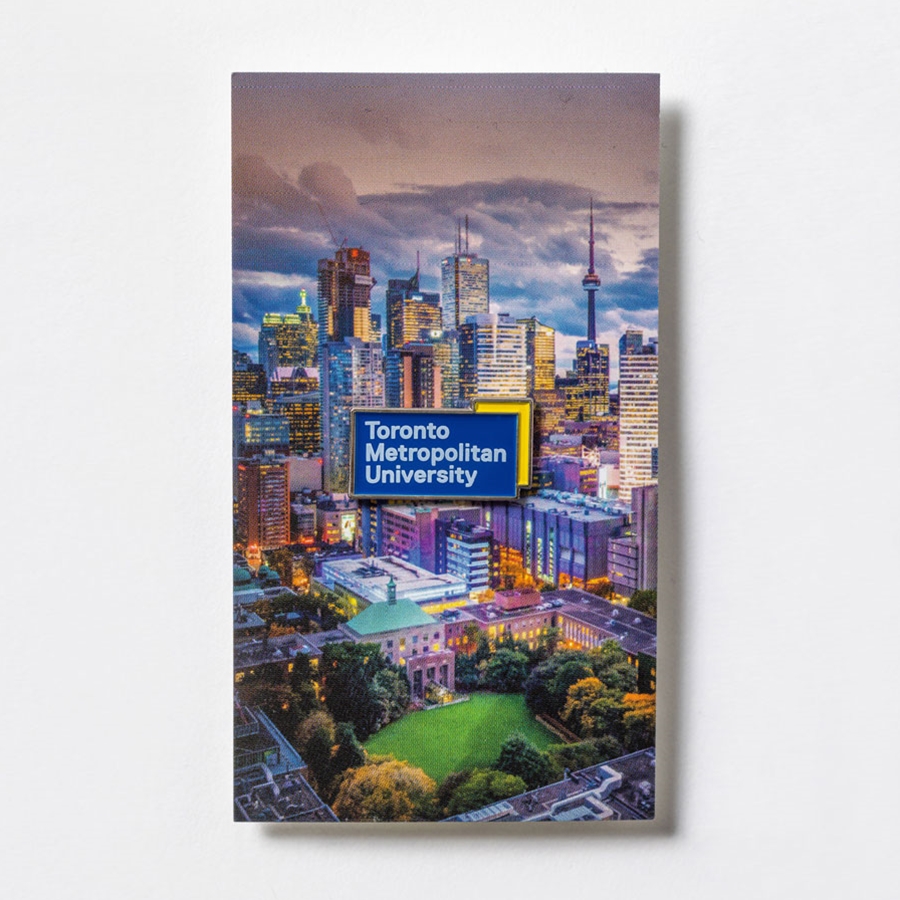 Mounted on cardstock featuring an artist's rendering of the Toronto Metropolitan University campus & Toronto, this soft enamel lapel pin is the perfect addition to your TMU wardrobe. The pin is 1" wide