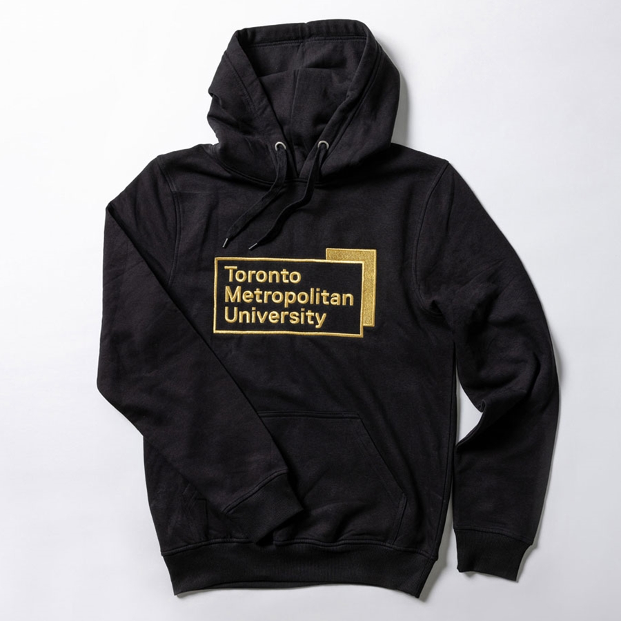 A black pullover fleece hoodie features the "Toronto Metropolitan University" corporate logo, embroidered in gold metallic thread, front and centre.