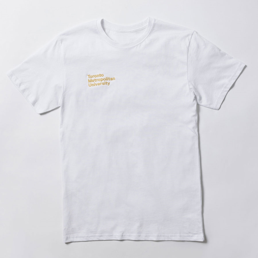 A short-sleeved white t-shirt features a printed "Toronto Metropolitan University" small stacked wordmark logo on the front right chest in embroidered metallic gold.