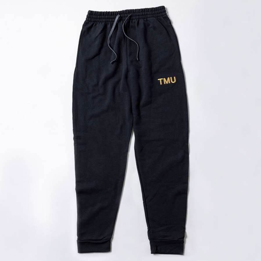 A black fleece sweatpants features "TMU" on the left hip, embroidered with gold metallic thread.